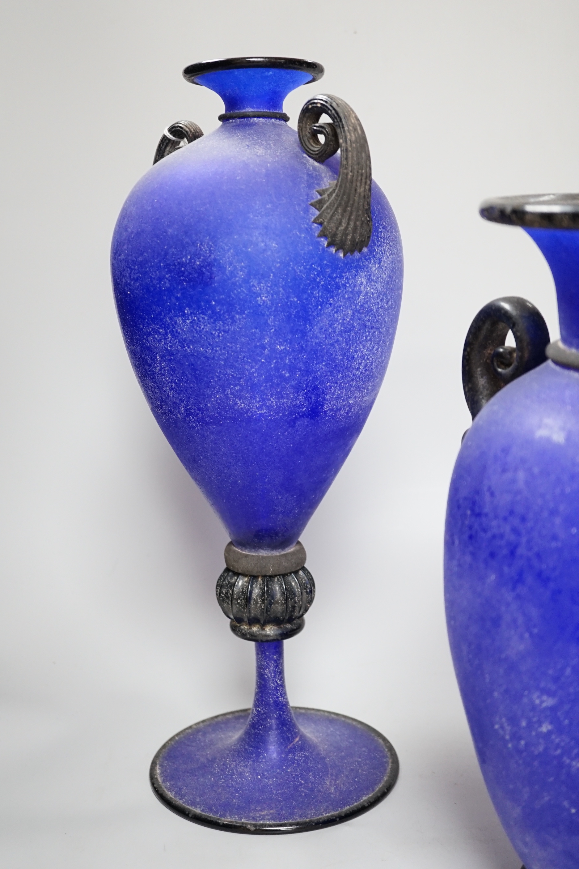 Two glass twin handled Roman style urns including a pedestal example, one signed Gambaro & Poggi, the largest 43cm high